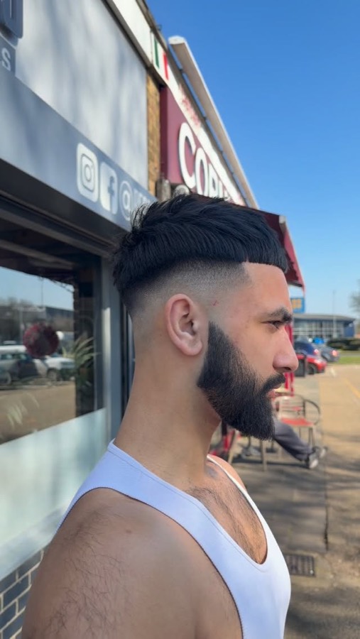 A fade and full beard in the window light.