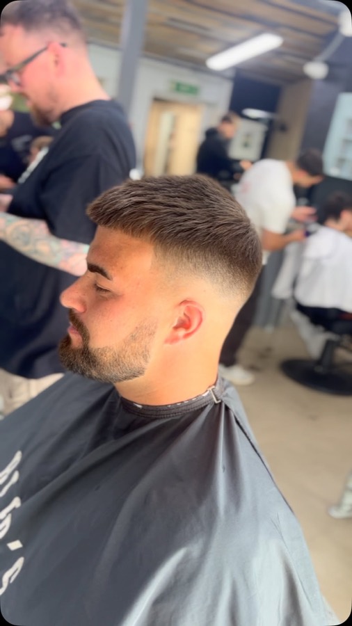 A fade and a trimmed beard, side profile.