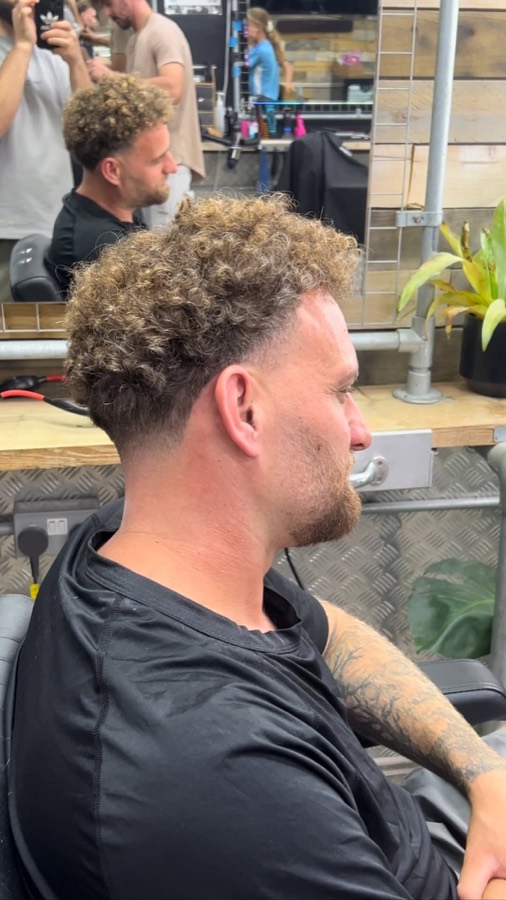 Loose curls left long on top over a taper.